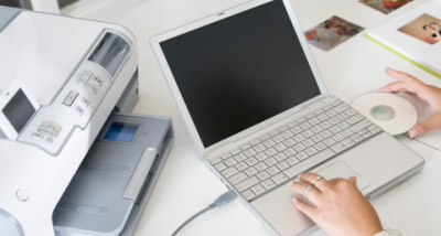updating-a-printer-driver Laptop On A Desk With Driver Disc Being Inserted