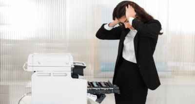 why-is-my-printer-offline-intro-image Stressed Woman Staring At A Broken Printer